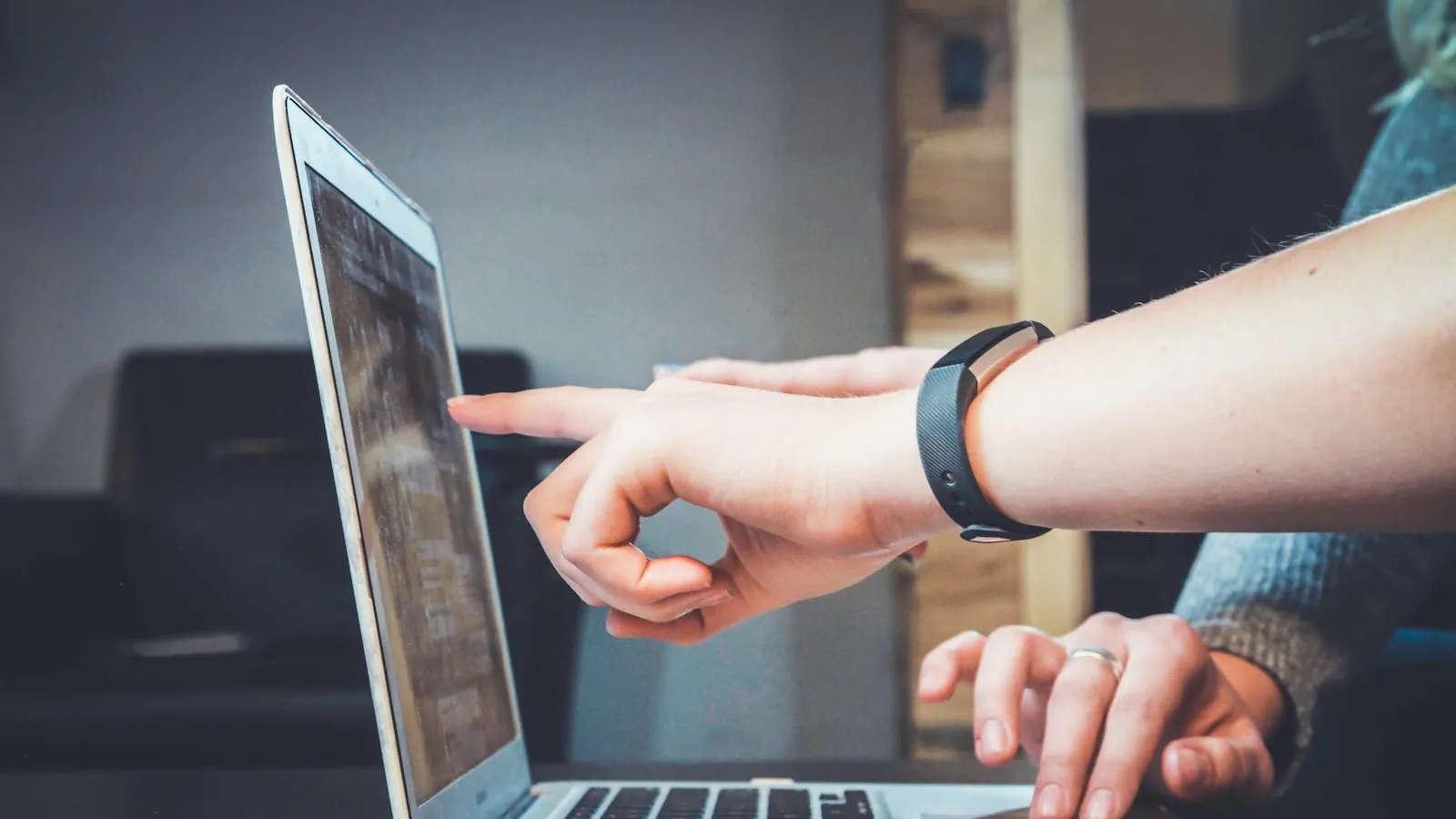 Person pointing at a laptop screen during a review