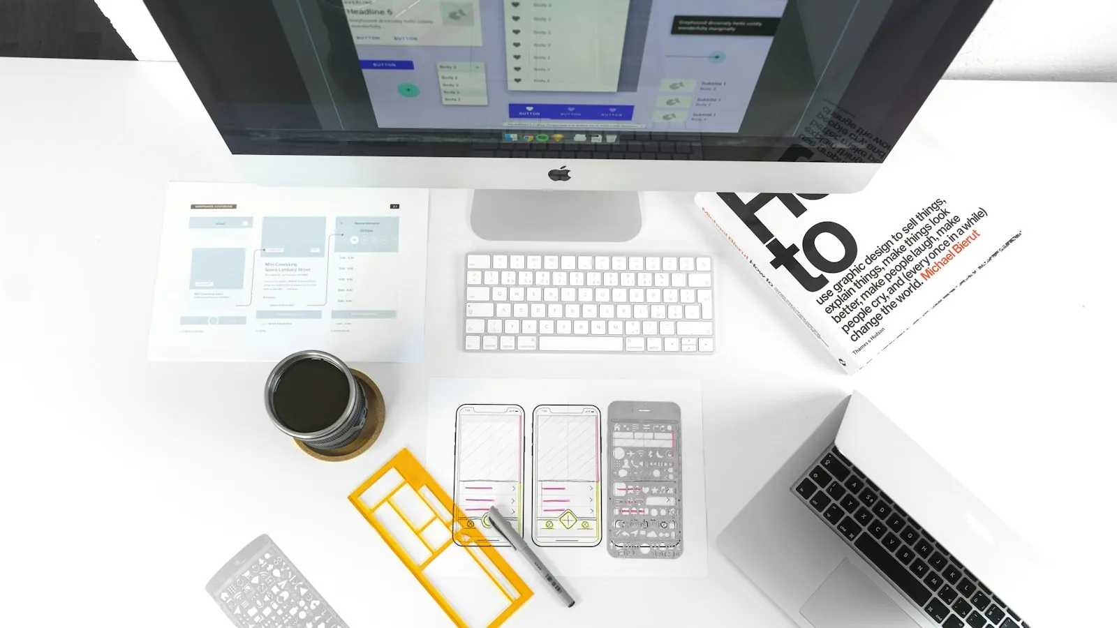 Overhead view of a designer's desk with wireframe stencils and a laptop