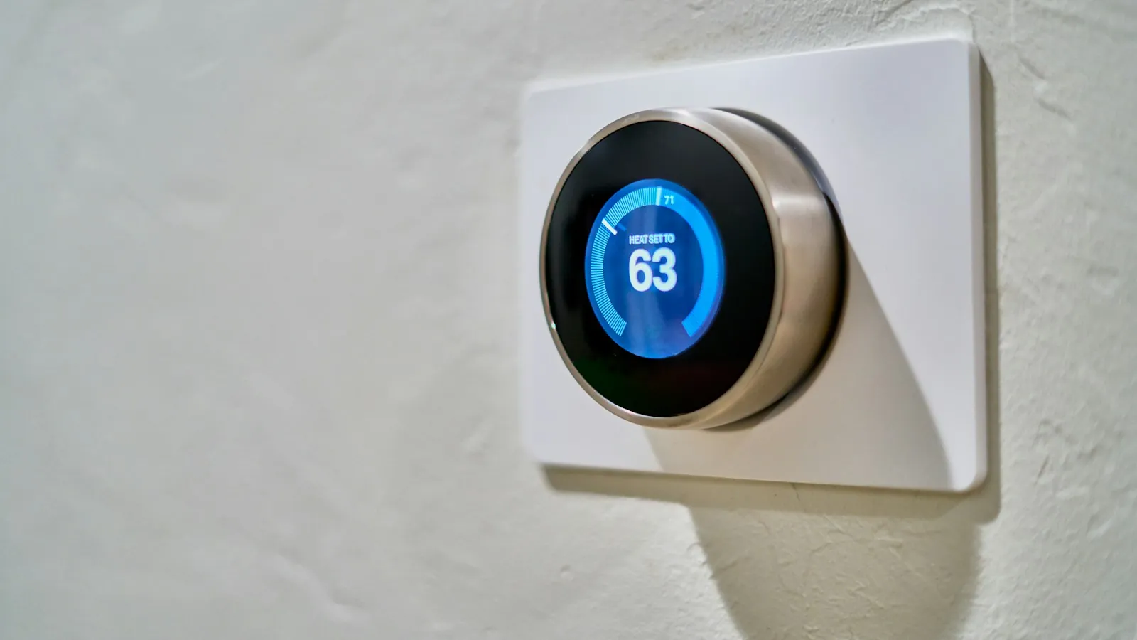 Close-up of a round smart thermostat dial on a wall
